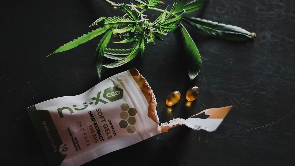 Gélules de CBD sorties d'un sachet, feuille de chanvre à côté