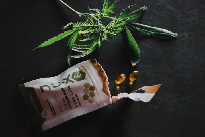 Gélules de CBD sorties d'un sachet, feuille de chanvre à côté