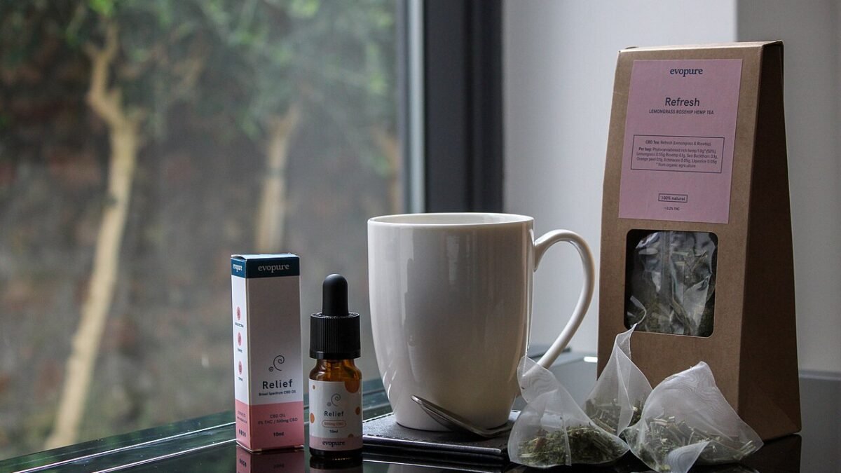 Tasse et flacon de CBD devant une fenêtre