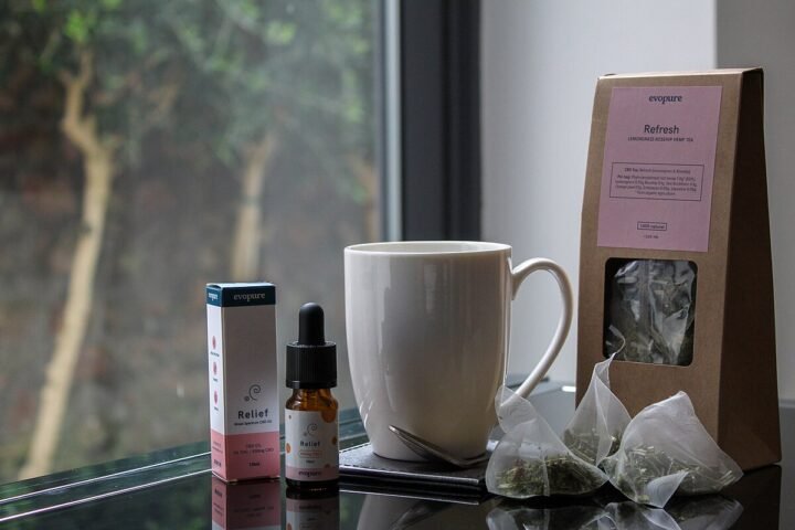 Tasse et flacon de CBD devant une fenêtre