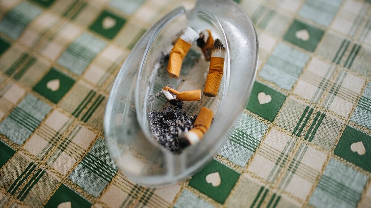 Cendrier en verre rempli de mégots sur une nappe à carreaux