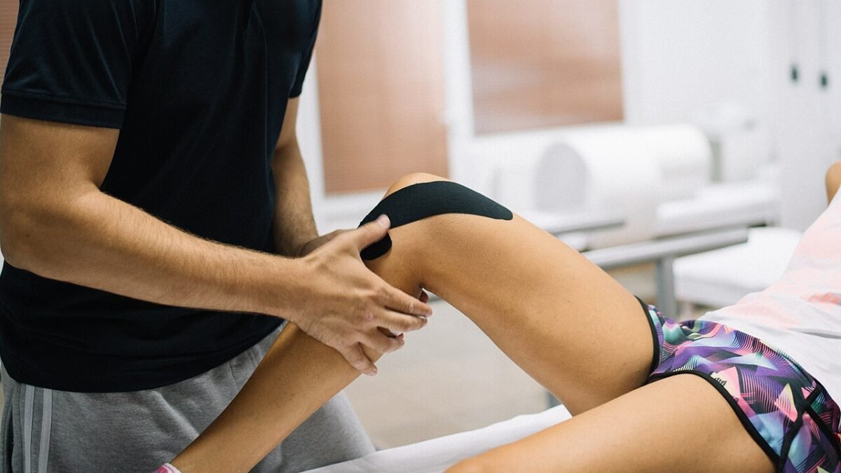 Massage du genou d'une personne allongée, mains du praticien sur la rotule
