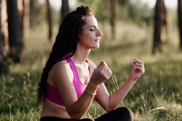 Femme assise en méditation dans une forêt, lumière dorée du soir
