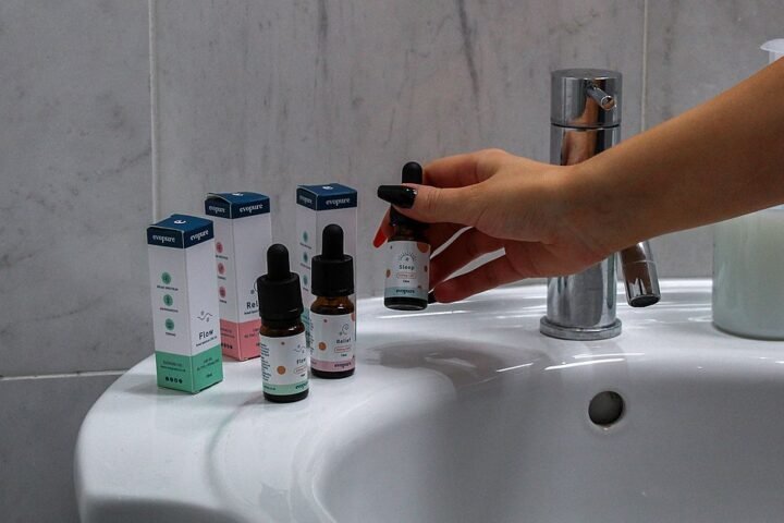 Main attrapant un flacon d'huile de CBD sur le bord d'un lavabo