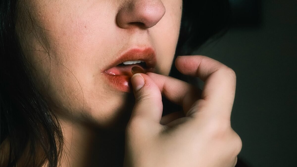 Gros plan sur une femme portant une gélule à sa bouche