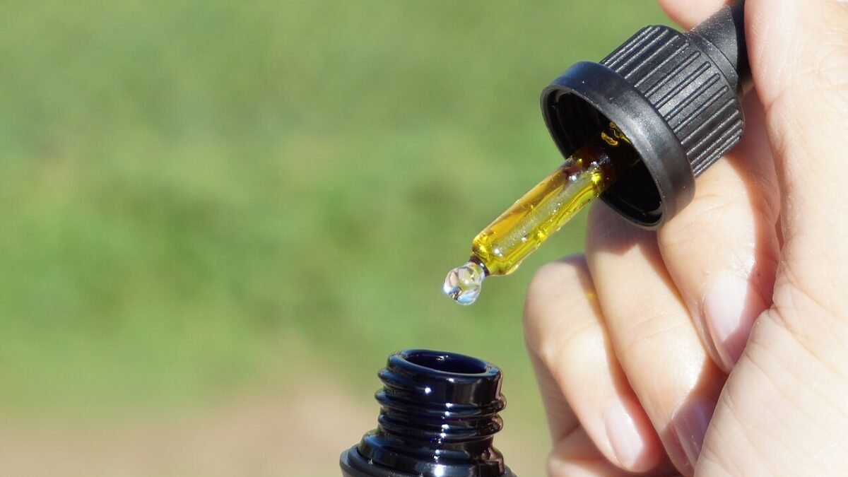 Flacon d'huile de CBD tenu à la main en extérieur