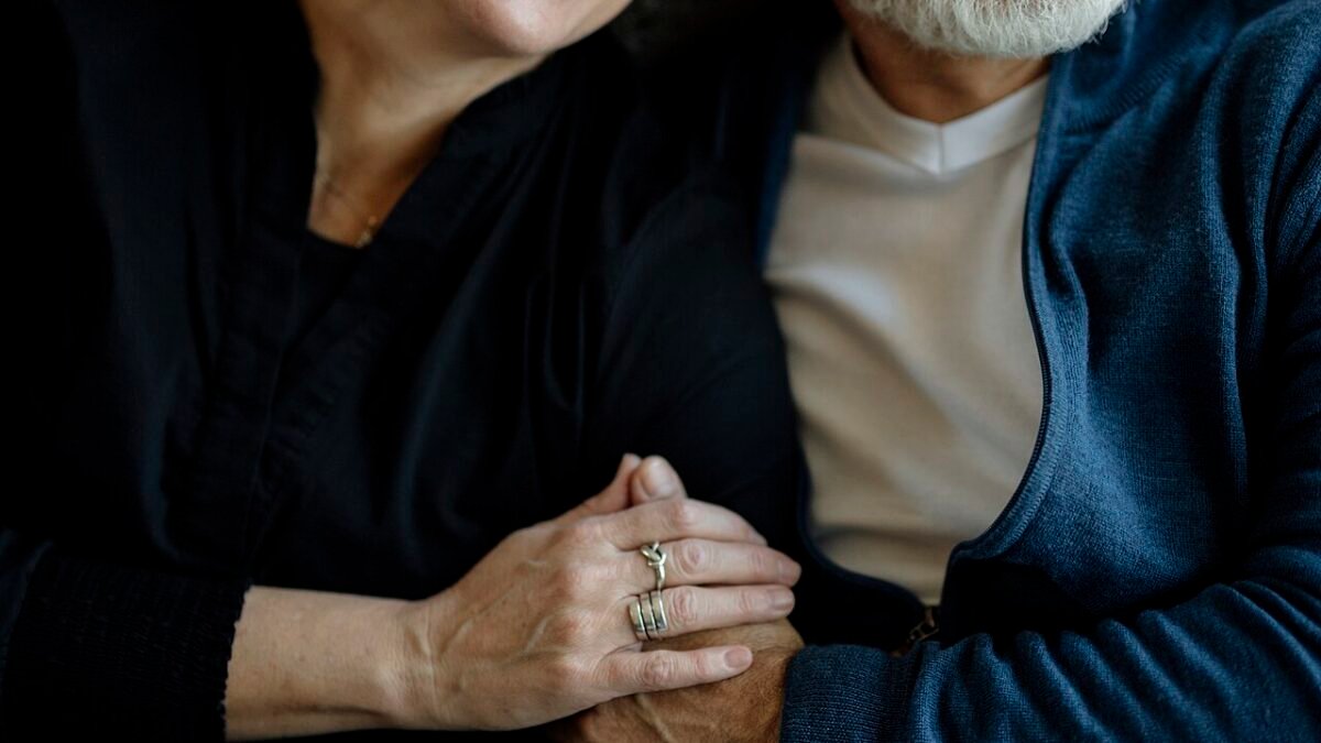 Couple d'âge mûr assis sur un canapé, souriant et se tenant la main