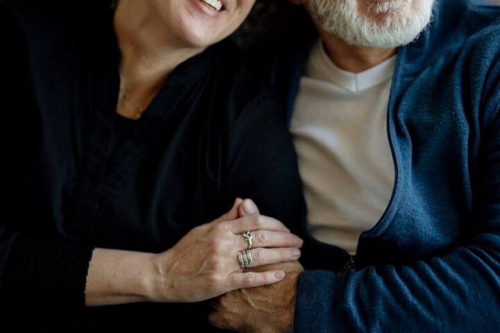 Couple d'âge mûr assis sur un canapé, souriant et se tenant la main