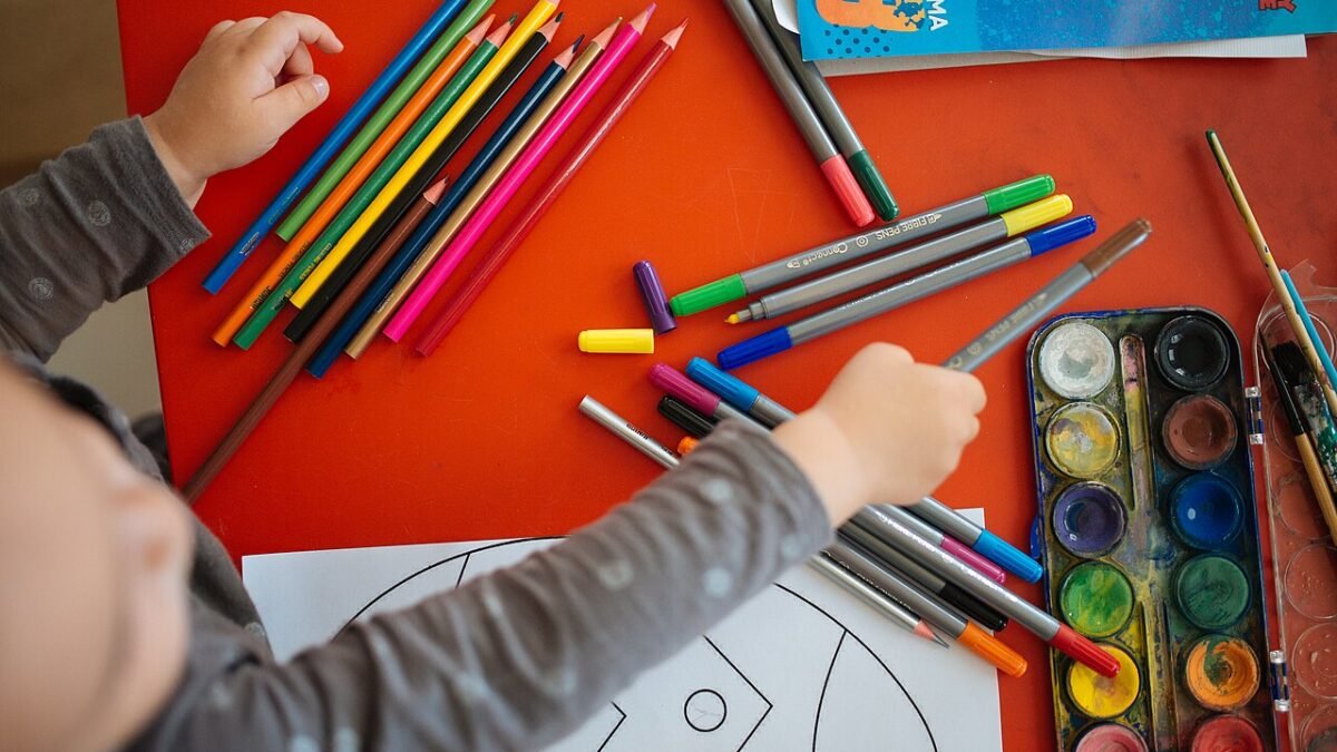 Mains d'enfant dessinant avec des crayons de couleur, vu du dessus