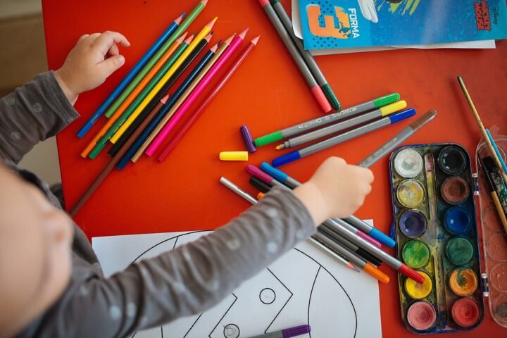 Mains d'enfant dessinant avec des crayons de couleur, vu du dessus