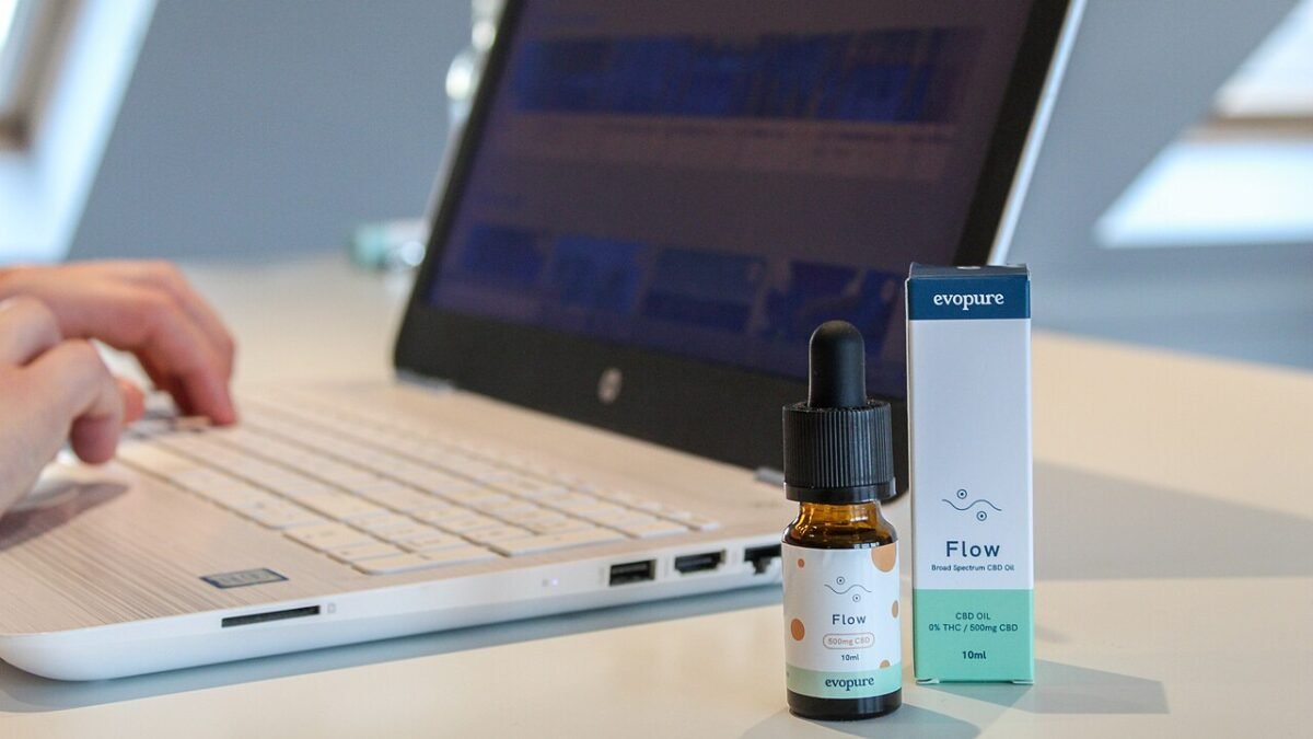 Flacon d'huile de CBD posé sur un bureau à côté d'un ordinateur portable