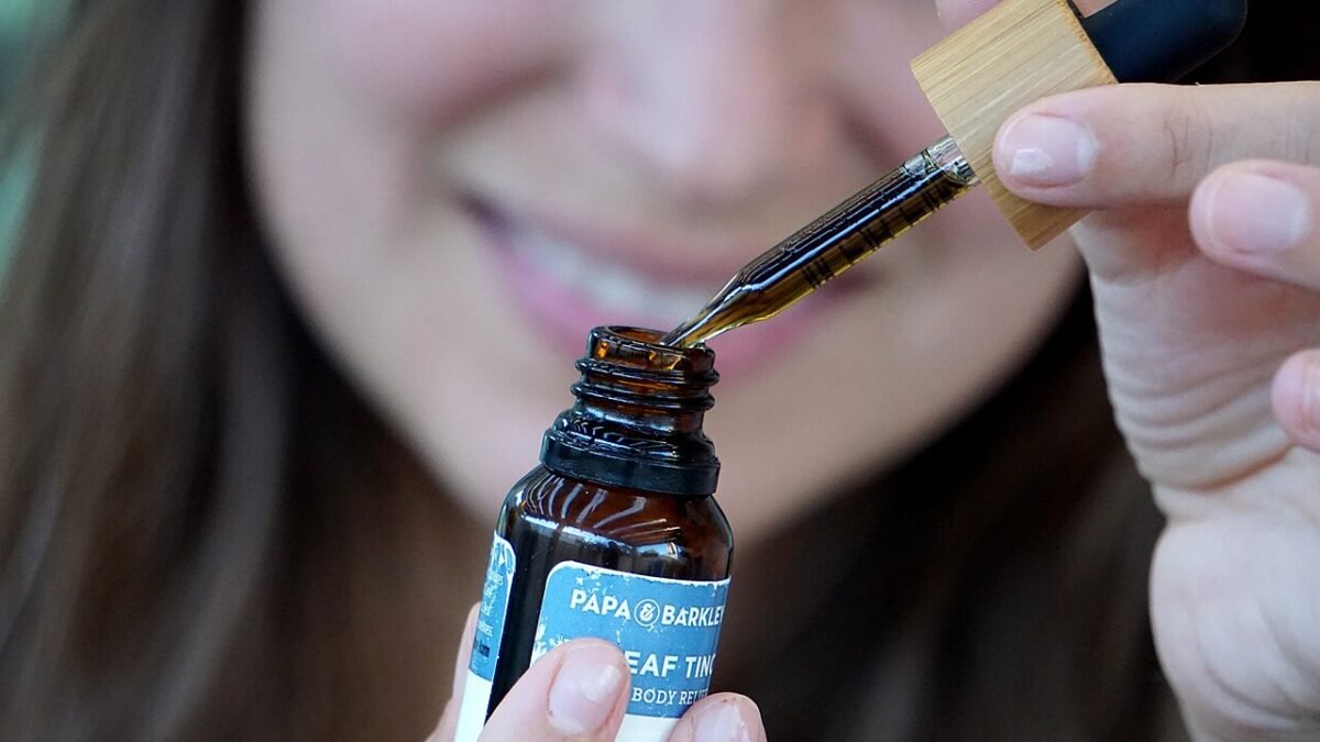 Femme dosant des gouttes d'huile de CBD avec une pipette