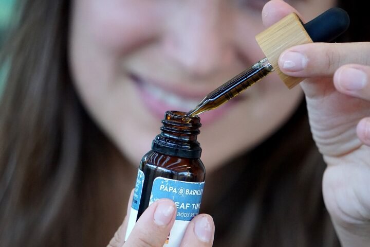 Femme dosant des gouttes d'huile de CBD avec une pipette