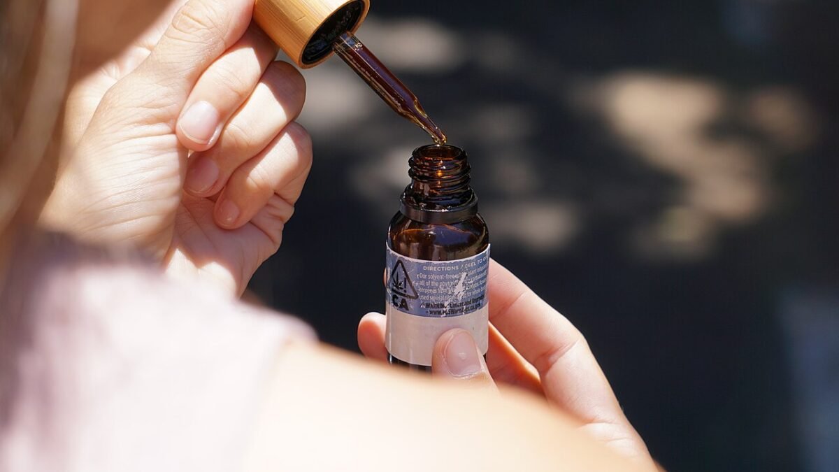 Main tenant une pipette au-dessus d'un flacon d'huile de CBD