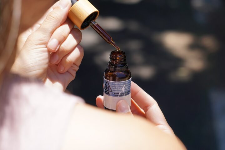 Main tenant une pipette au-dessus d'un flacon d'huile de CBD