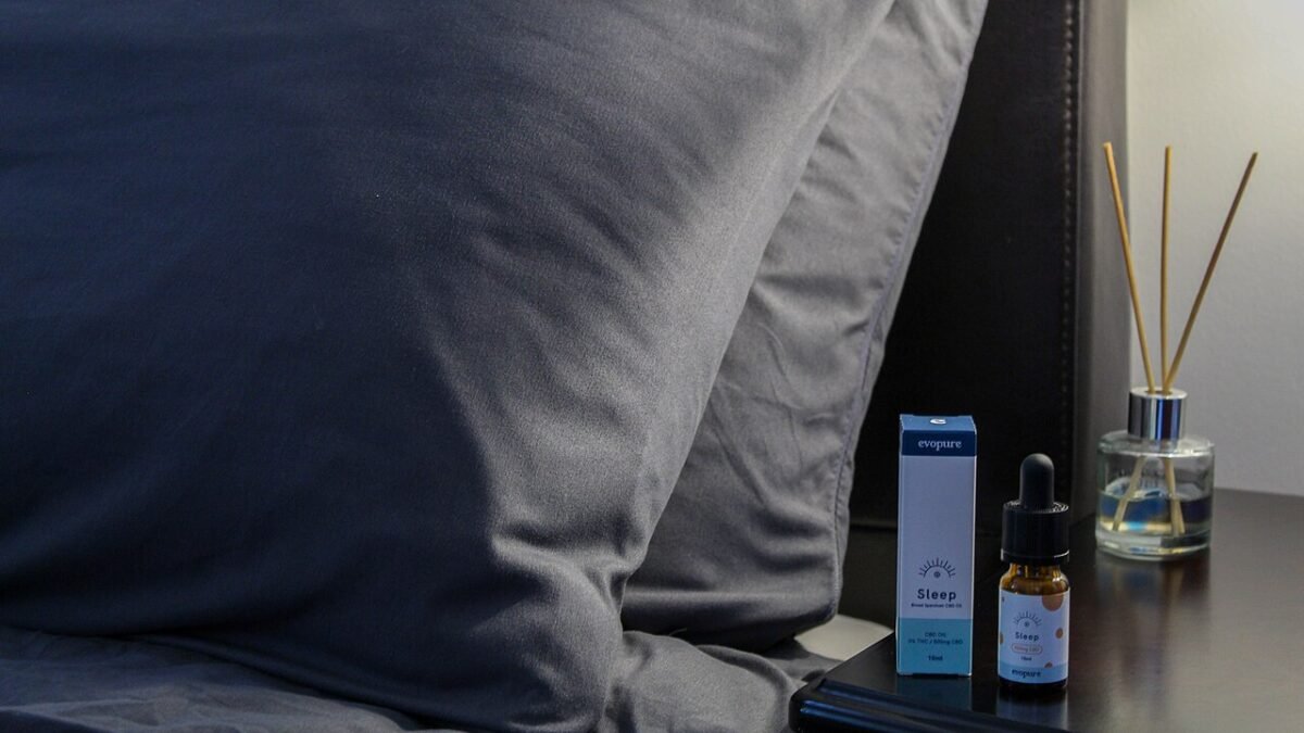 Flacon d'huile de CBD sur une table de chevet, lit en arrière-plan