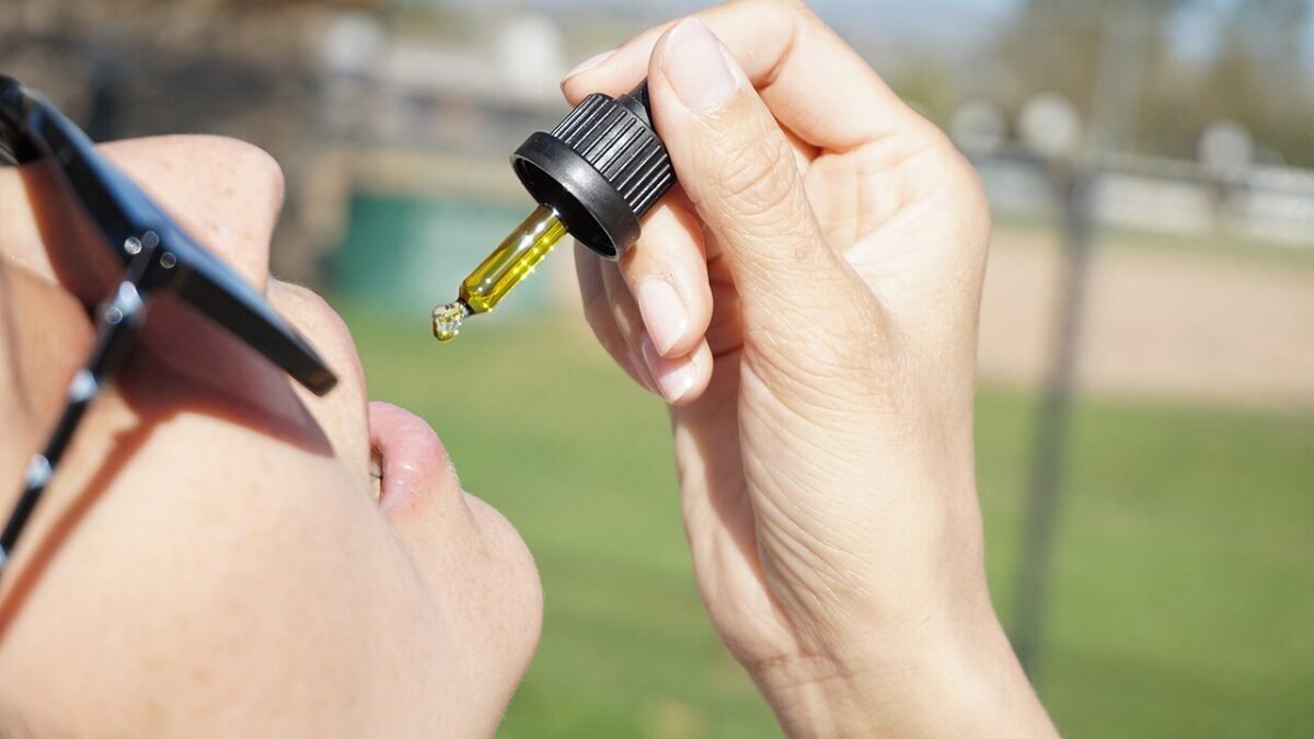 Mains tenant un flacon et une pipette d'huile de CBD en plein air
