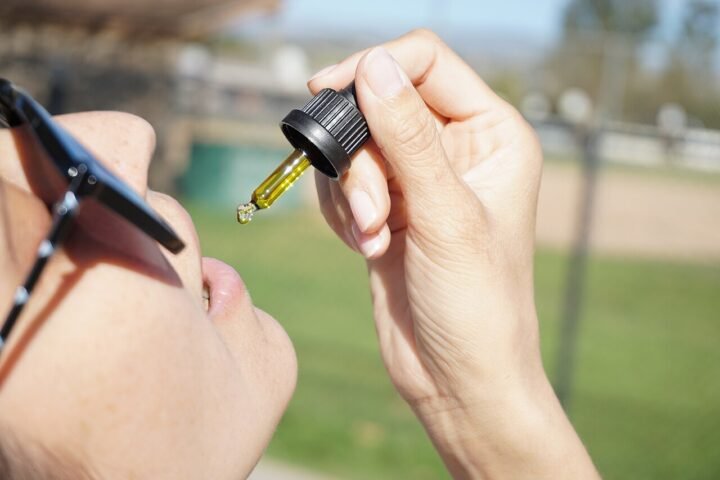 Mains tenant un flacon et une pipette d'huile de CBD en plein air