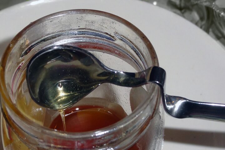 Cuillère plongée dans un pot de miel