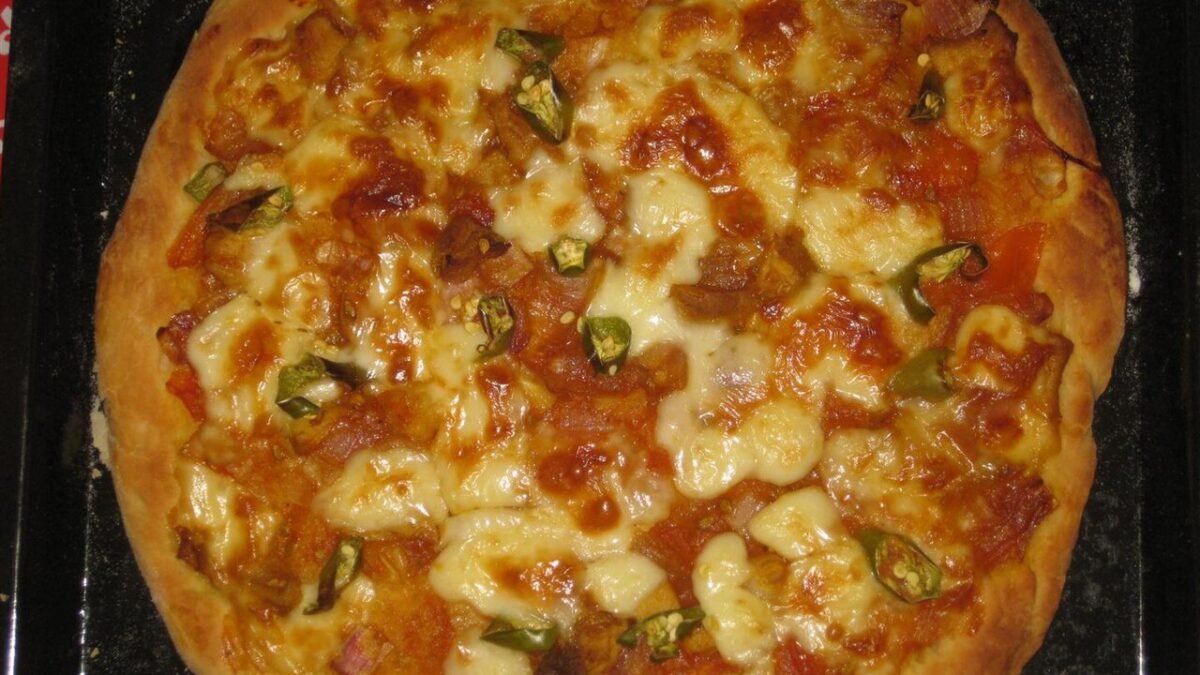 Pizza maison sortie du four sur une plaque noire