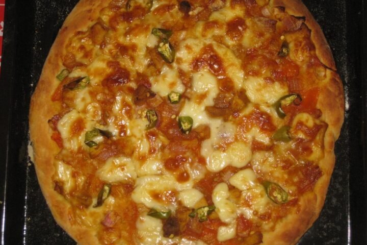 Pizza maison sortie du four sur une plaque noire