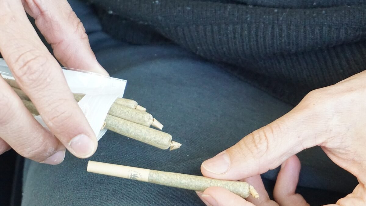 Mains tenant plusieurs pré-rolls de CBD au-dessus d'un plateau