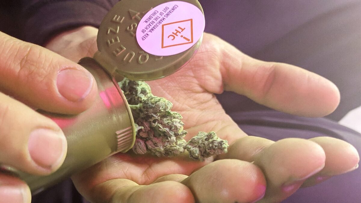 Main tenant un contenant de produit de cannabis médical étiqueté