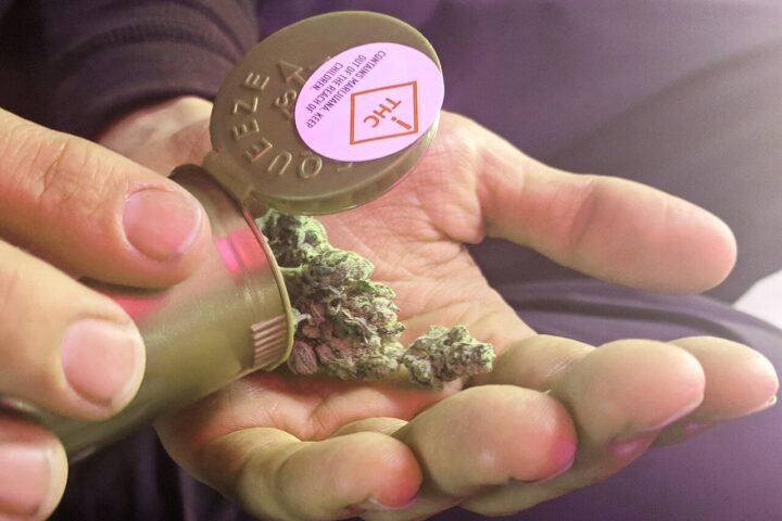 Main tenant un contenant de produit de cannabis médical étiqueté