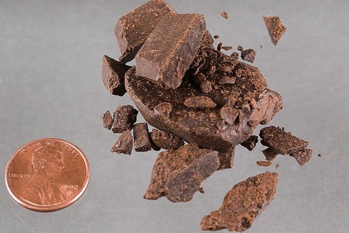 Morceaux de résine de chanvre brun clair à côté d'une pièce de monnaie