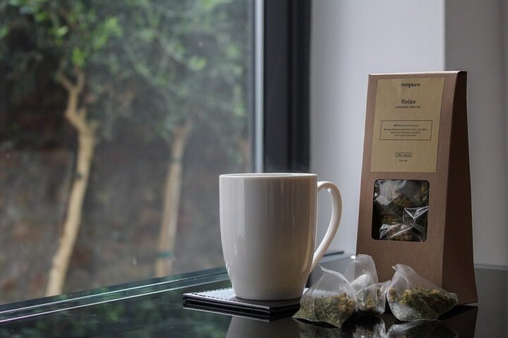 Tasse et sachets d'infusion au chanvre devant une fenêtre